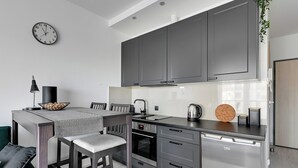 A modern kitchen with grey cabinets, a built-in oven, and a dishwasher. - Albatross Tower by Grand Apartments (Gdansk)