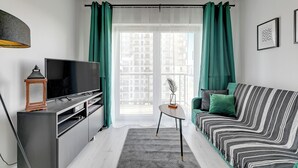 A modern living room with a flat-screen TV, a small table, a sofa, and a large window with curtains. - Albatross Tower by Grand Apartments (Gdansk)