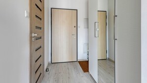 A hallway with wooden doors, a white wall, and a light-colored floor. - Albatross Tower by Grand Apartments (Gdansk)