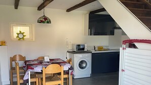 Cocina compacta con lavadora, microondas y comedor con mesa y sillas.