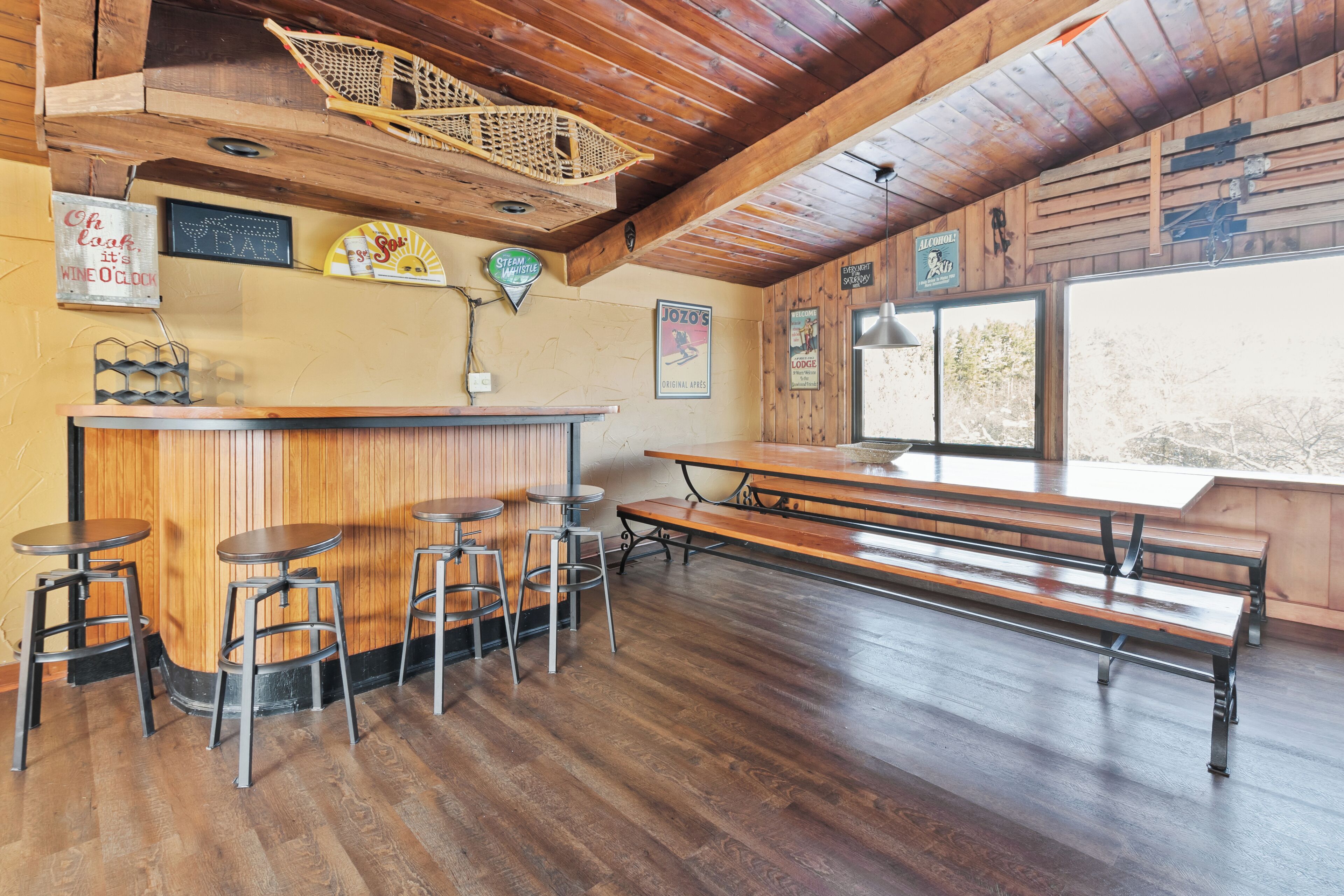 A rustic bar area with wooden stools, a long bench, and a wooden counter.