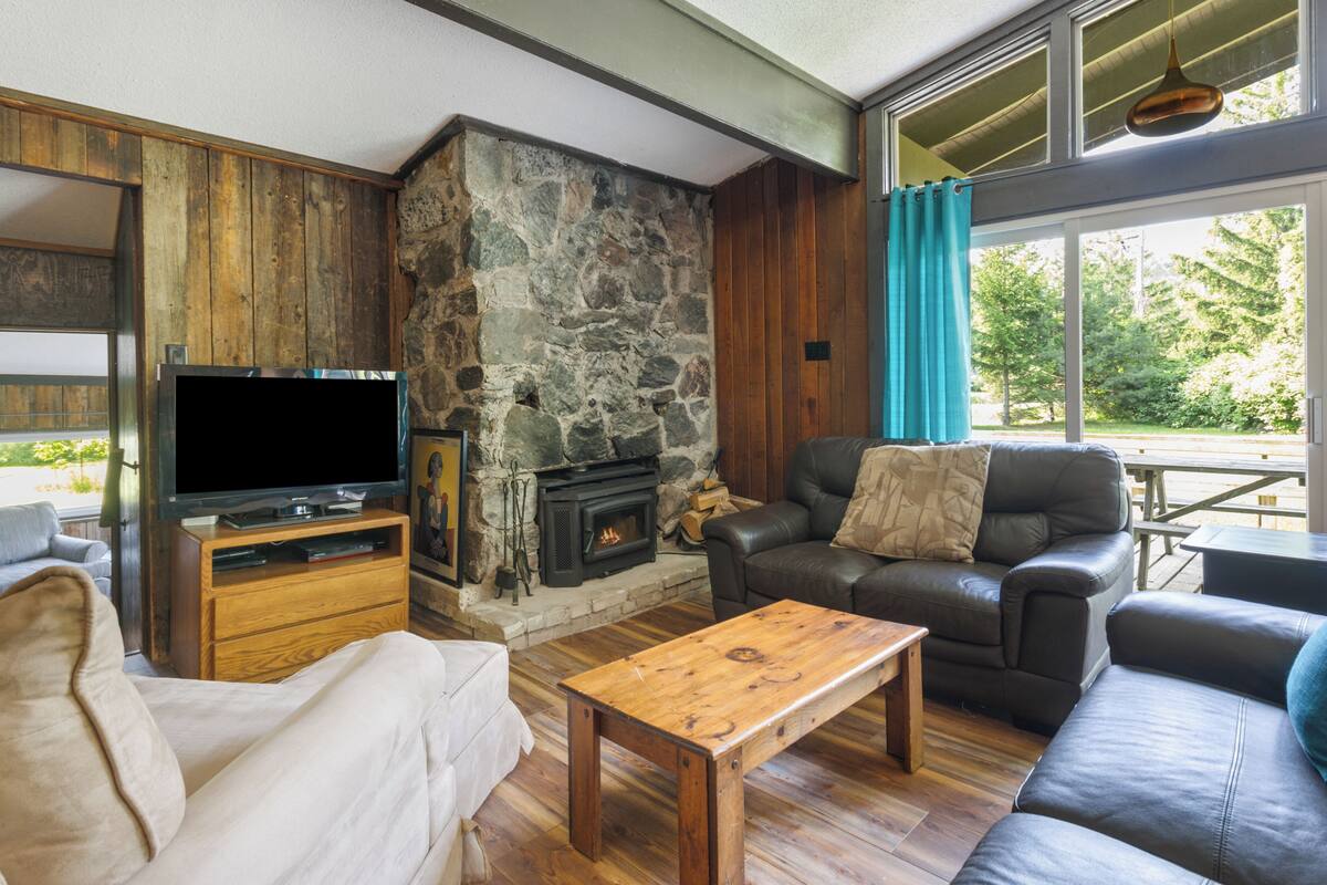 Una sala de estar acogedora con chimenea de piedra, sofás de cuero y un televisor de pantalla plana.