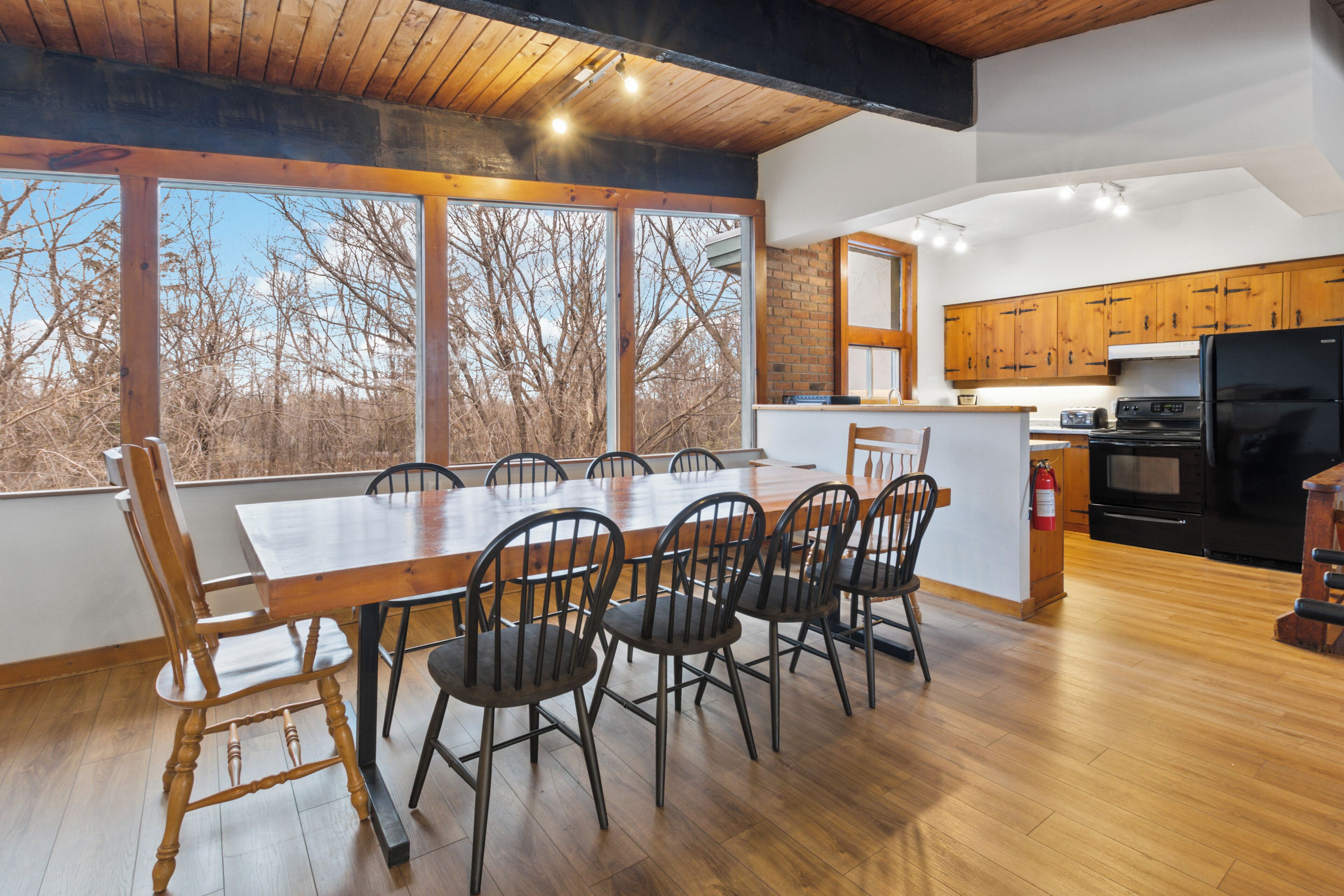 Une cuisine moderne avec des meubles en bois, un grand îlot central et un coin repas comprenant une table et des chaises en bois.