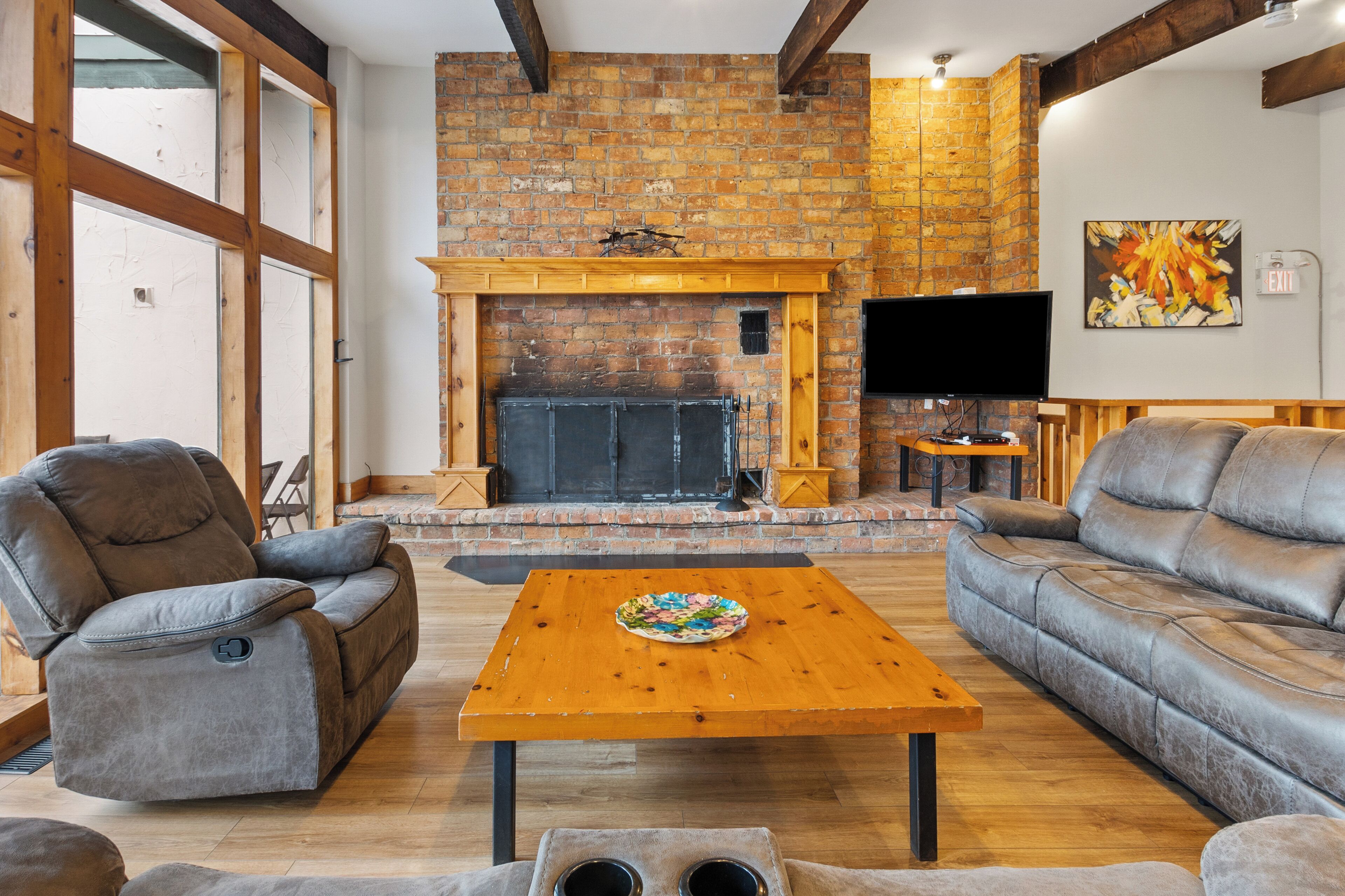 A living room with a fireplace, leather sofas, a wooden coffee table, and a television.