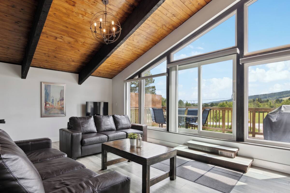 Una sala de estar moderna con un sofá de cuero, una mesa de centro y un ventanal con vistas al exterior.
