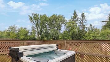 Relax in a hot tub on a deck with a view of the surrounding trees.