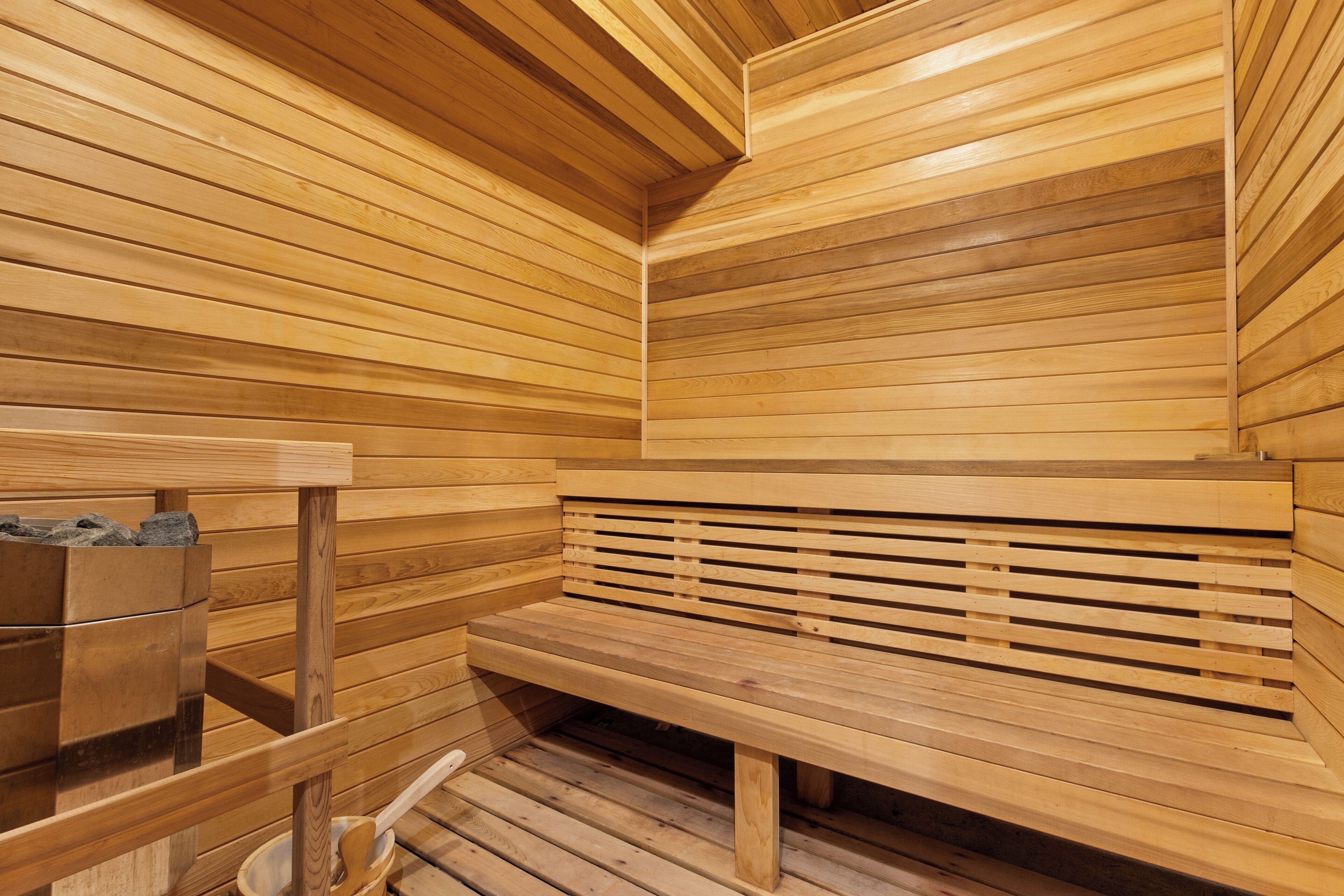 Una sauna de madera con bancos y una pileta de piedra.
