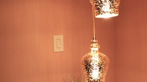 Ein runder Glastisch mit Blumen in einer Vase und einer kleinen Schachtel, beleuchtet von zwei hängenden Lampen.