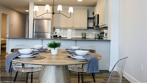 Una cocina moderna con electrodomésticos de acero inoxidable, un comedor con una mesa redonda y un candelabro.