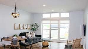 Amplia sala de estar con comedor, un sofá, una mesa de centro y un televisor montado en la pared.