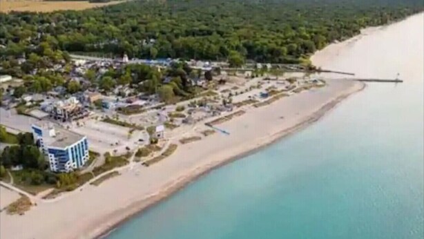 Vista aérea de una zona costera con playa, un muelle y un grupo de edificios.