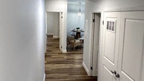 Un pasillo con piso de madera, paredes blancas y una lámpara en el techo.