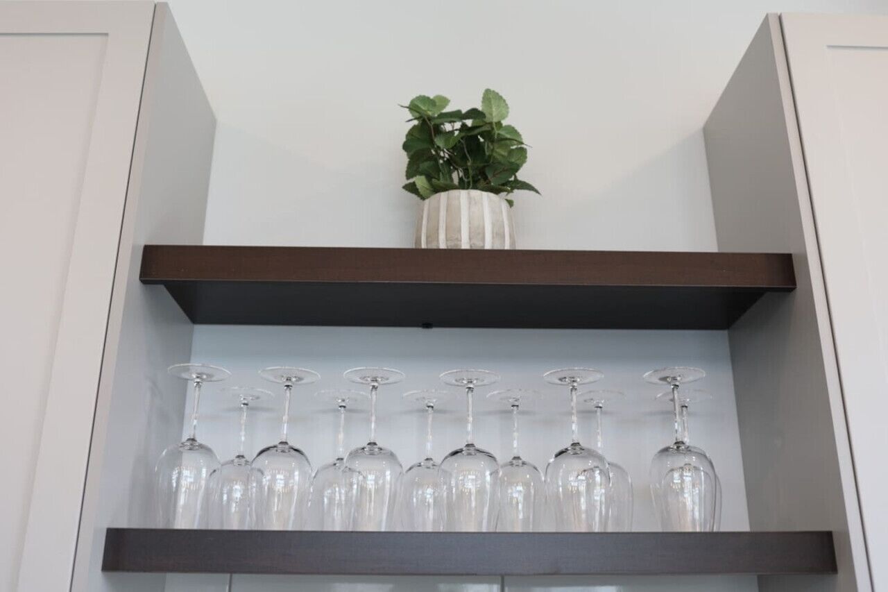 Una estantería con una planta en maceta y varias copas de vino.