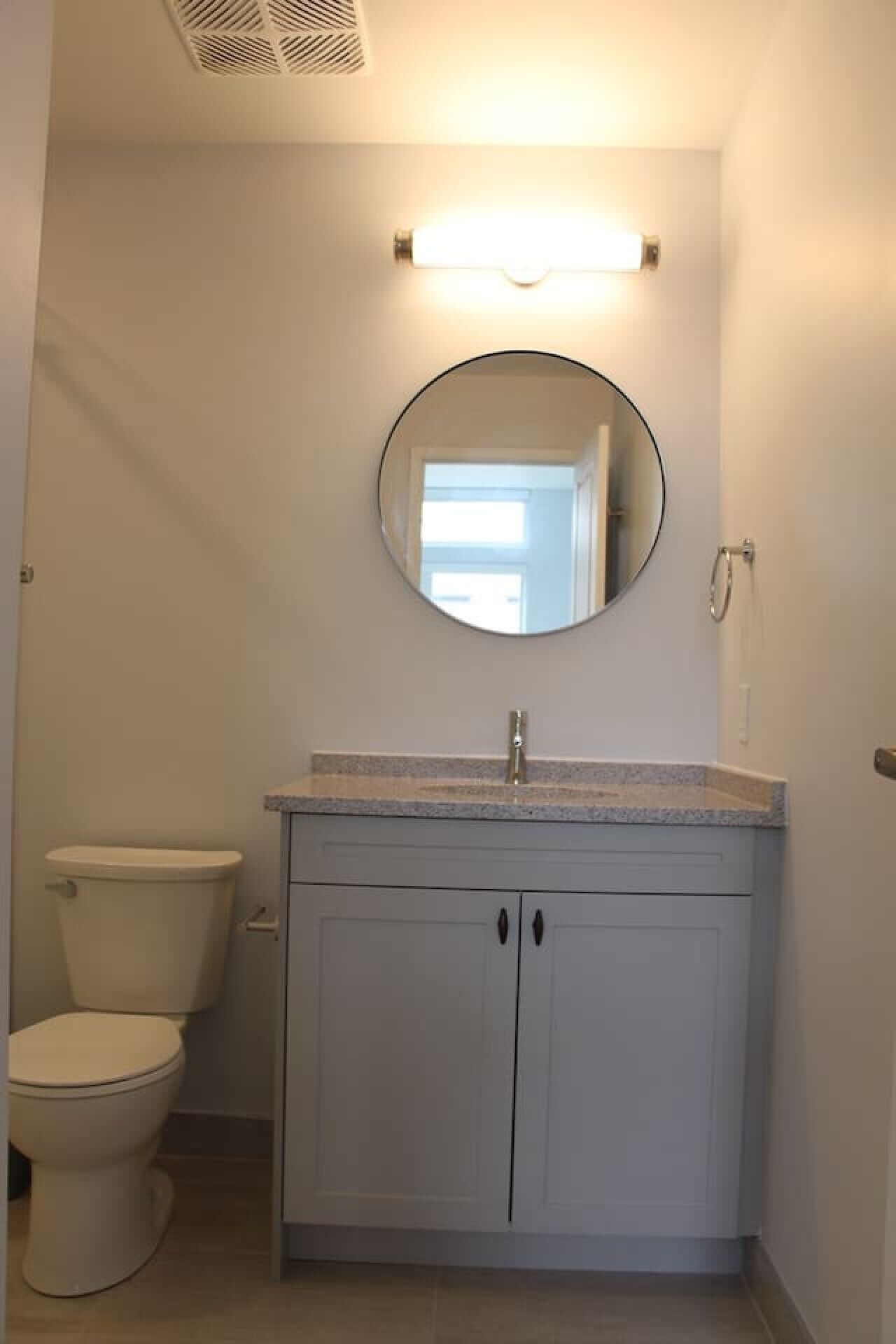 A bathroom with a toilet, a sink with a mirror above it, and a showerhead.