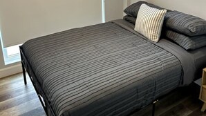 Un dormitorio con cama, ventana y mesita de noche.