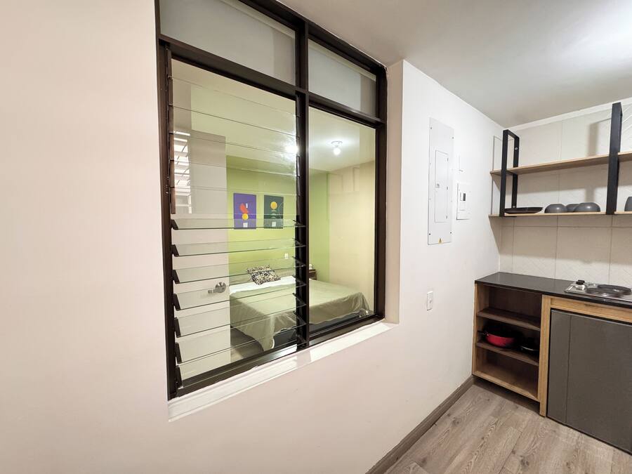 A compact kitchen with a built-in stove, a wooden countertop, and a small shelf unit.