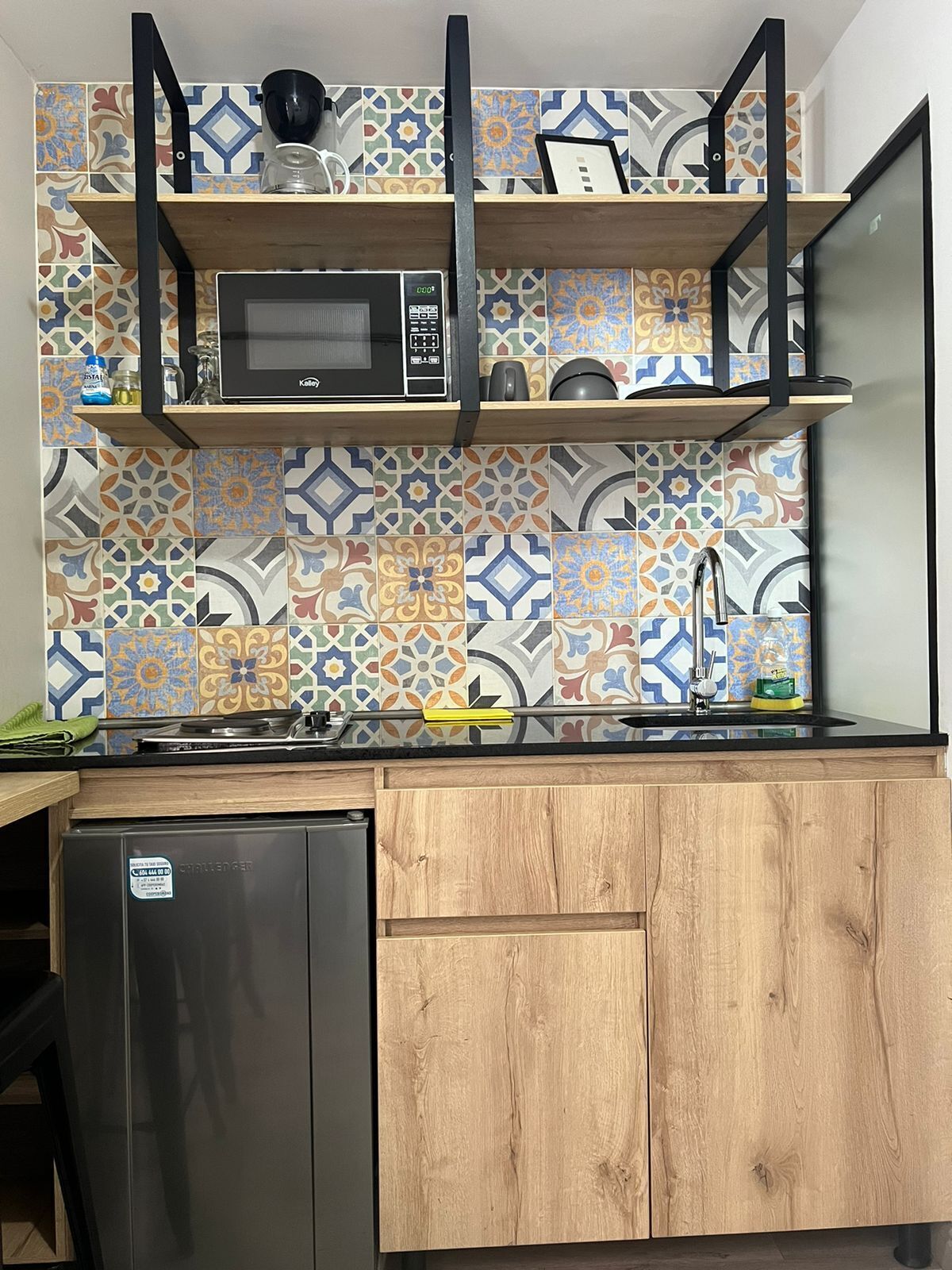 A kitchen with a microwave, wooden cabinets, and a patterned backsplash.
