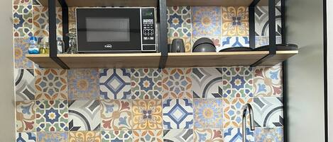 A kitchen with a microwave, wooden cabinets, and a patterned backsplash.