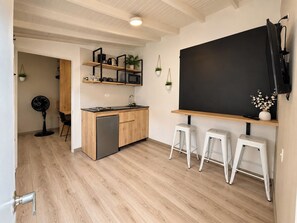 A compact kitchen with a dishwasher, wooden cabinets, and a blackboard on the wall. - Manila by Roots Rentals (Medellín)