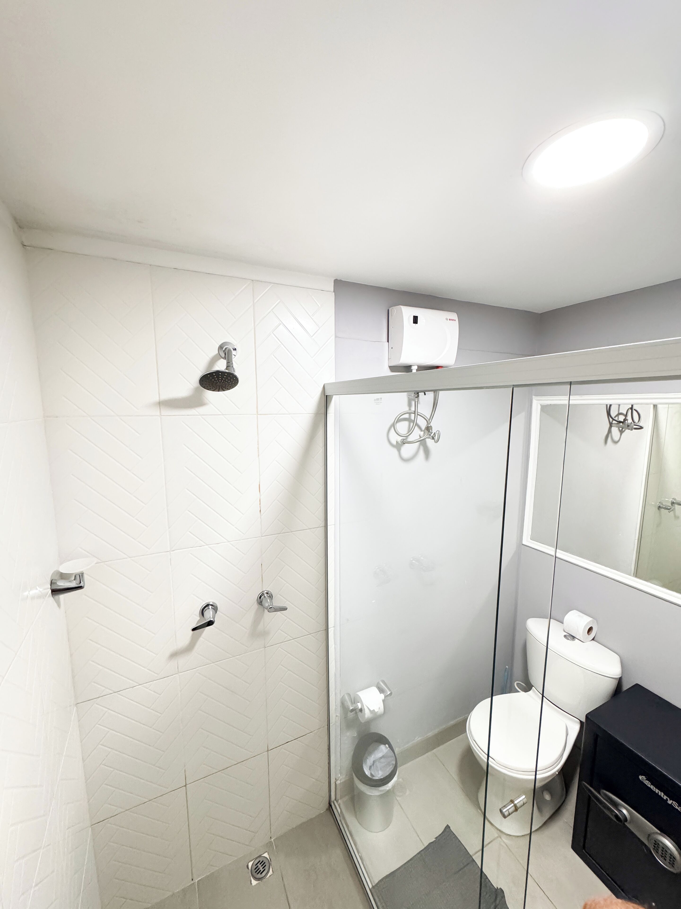 Un baño moderno con cabina de ducha de vidrio, inodoro y lavamanos con encimera negra.