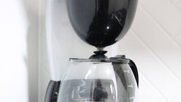 A black coffee maker with a clear glass carafe on a black countertop.