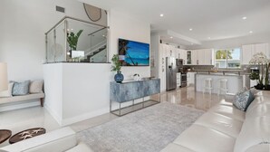 Een moderne keuken met witte kastjes, een centraal eiland en een groot raam.