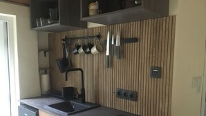 A modern kitchen with a built-in stove, a sink, and a wooden backsplash. - Tiny House with WiFi in Lebehn (Krackow)