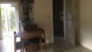 A compact kitchen with a dining table and chairs, a built-in oven, and a small window. - Tiny House with WiFi in Lebehn (Krackow)