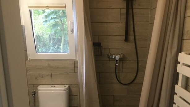 A small bathroom with a toilet, a shower, and a window. - Tiny House with WiFi in Lebehn (Krackow)