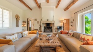 Un salon chaleureux avec une cheminée, des poutres en bois et une grande fenêtre.