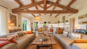 Un salon spacieux doté d’un haut plafond en bois, d’une table basse centrale en bois et de coins salon confortables.