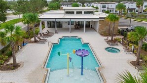 Ein Swimmingpool mit Wasserrutsche und Liegestühlen, umgeben von Palmen und einem Gebäude mit einer überdachten Terrasse.