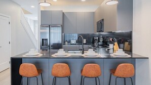 A modern kitchen with a central island, bar stools, and a staircase leading to another level. - TR17145BD - 3 bedrooms home close to Disney (Clermont)