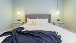 A neatly made bed with a white headboard, two bedside tables with lamps, and a dark blue throw blanket. - TR17145BD - 3 bedrooms home close to Disney (Clermont)