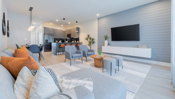 A modern living room with a sofa, armchairs, and a coffee table. There is a kitchen in the background with a dining area. - TR17145BD - 3 bedrooms home close to Disney (Clermont)