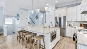 A modern kitchen with white cabinets, a central island with stools, stainless steel appliances, and pendant lighting. - Liahona: Private beach steps away, FREE golf cart, Heated pool, Gulf views (Miramar Beach)