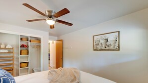 A bedroom with a bed, a ceiling fan, a closet with shelves, and a framed picture on the wall.
