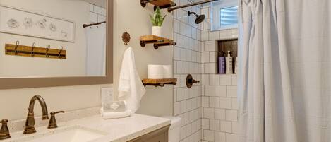 A bathroom with a white sink, a mirror, a shower curtain, and a toilet.