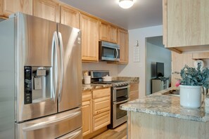 A modern kitchen with stainless steel appliances, wooden cabinets, granite countertops, and a potted plant. - 6 Mi to Denver: WFH-Friendly Duplex in Wheat Ridge (Wheat Ridge)