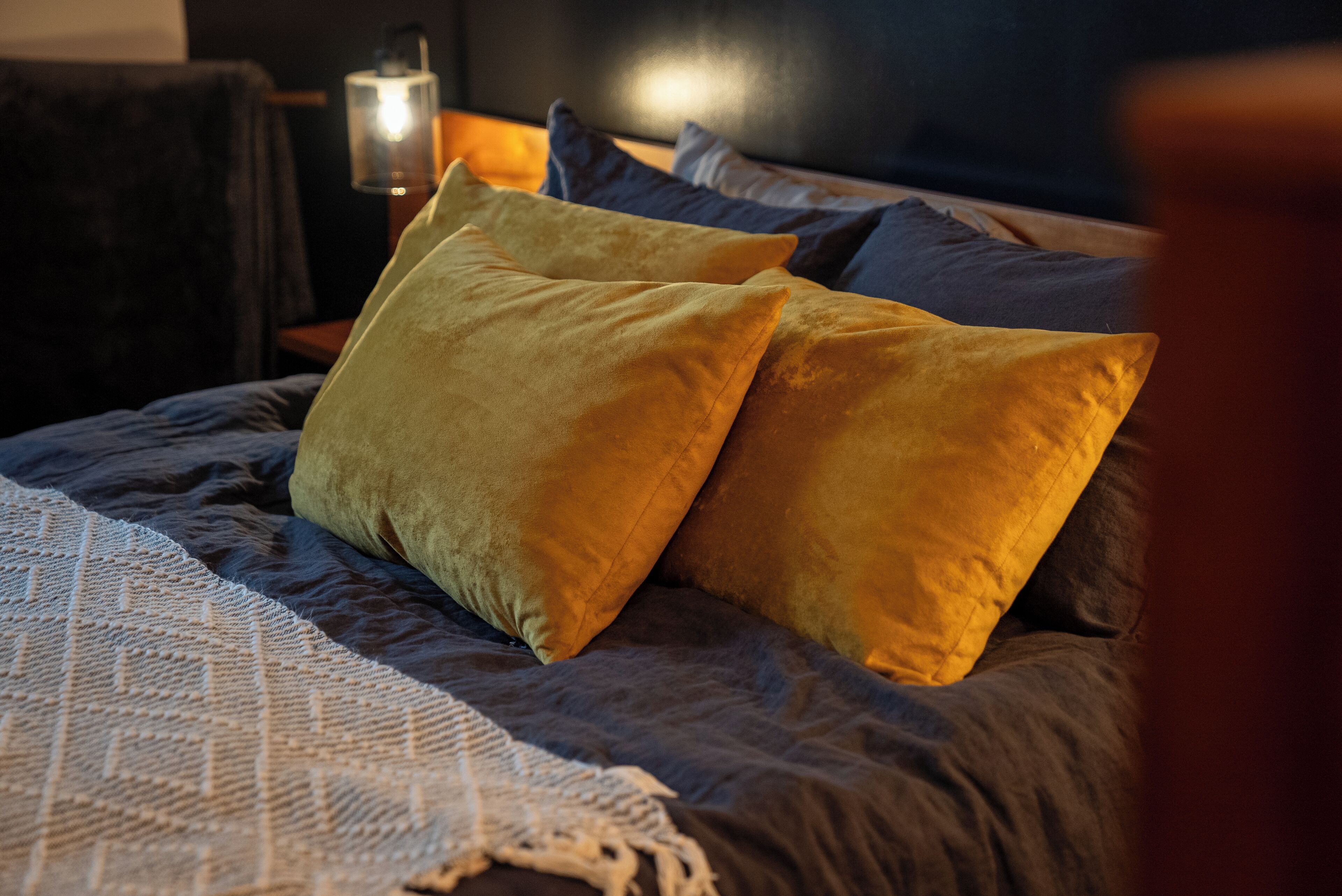 Uma cama com cobertor texturizado e duas almofadas.
