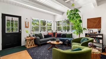 A modern living room with a sofa, armchairs, a coffee table, and a bookshelf.