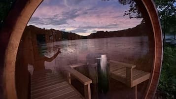 A circular wooden structure with a bench and a table, surrounded by a natural landscape and a body of water.