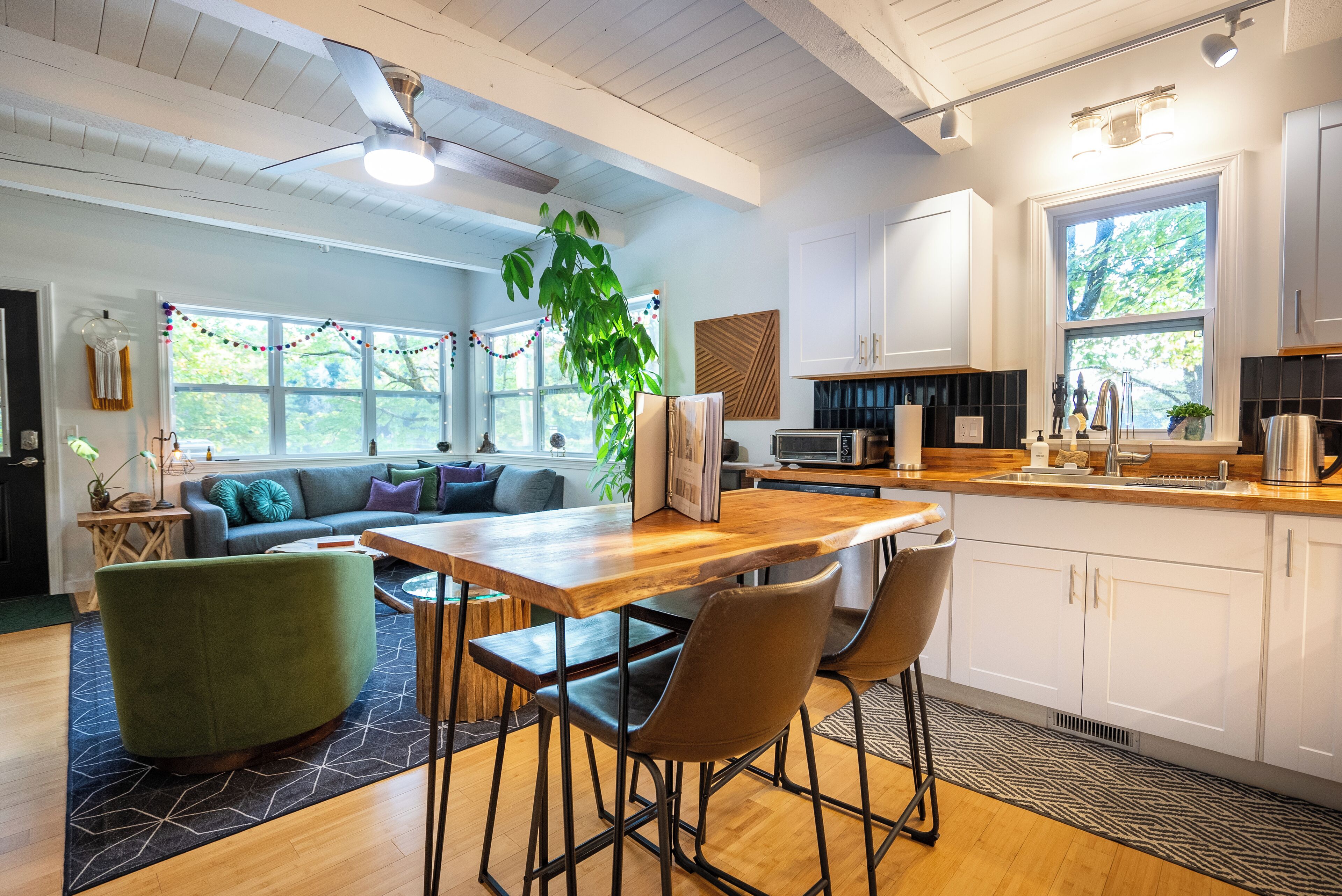 A modern kitchen with white cabinets, a wooden countertop, and a large window.