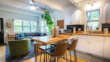 A modern kitchen with white cabinets, a wooden countertop, and a large window.