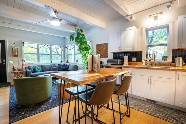 Una cocina moderna con armarios blancos, encimera de madera y un ventanal grande.