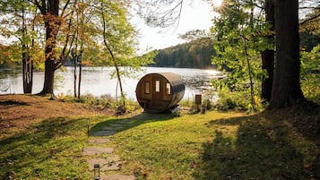 A wooden cabin by a lake surrounded by trees.