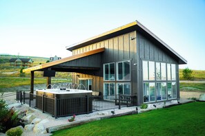 Una casa moderna con una terraza amplia, un jacuzzi y un porche espacioso con grandes ventanales.