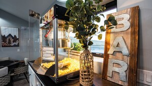A kitchen counter with a popcorn machine, a decorative wooden sign with letters, and a vase with green leaves.