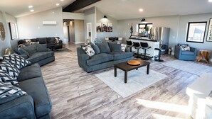 A spacious living area with two sofas, a coffee table, and a kitchen area with a refrigerator and sink.