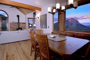 A dining area with a wooden table and chairs, a sofa, and a fireplace.